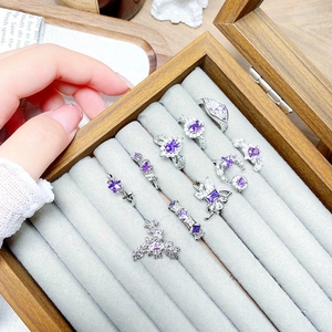 Elegant silver-tone ring set with purple zircon stones in a wooden jewelry display case
