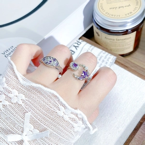 Detailed shot of silver rings with purple zircons and pearls on a model's hand