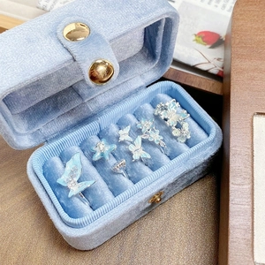 Détail de bagues papillon en émail bleu dans un coffret cadeau en velours chic