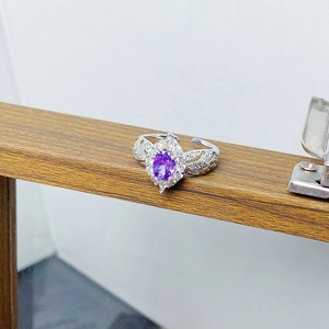 Macro shot of silver ring featuring oval purple stone and intricate wing-shaped diamond band