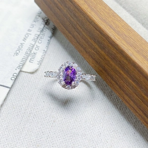 Macro view of oval purple gemstone ring with sparkling diamond halo setting