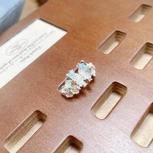 Vue détaillée de la bague papillon en émail bleu menthe avec zircons blancs sur bois