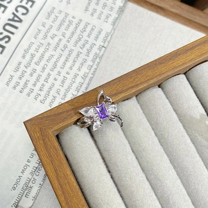 Macro shot of silver butterfly ring with purple rectangular gem and white cubic zirconia