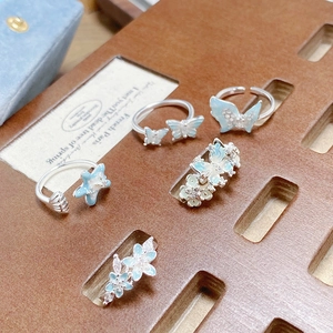 Gros plan de bagues en argent avec papillons en émail bleu clair sur support bois