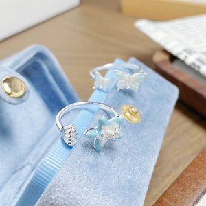 Détail macro de bagues en émail papillon et étoile de mer sur écrin en velours bleu
