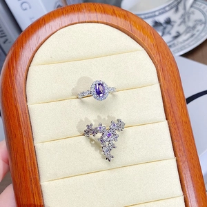 Macro detail of silver rings with purple zircons and floral patterns on beige display