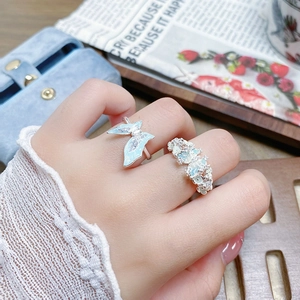 Détail de deux bagues papillon en argent avec émail bleu clair sur les doigts d'une femme