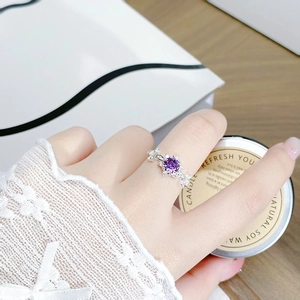 Close-up of elegant silver ring with purple gemstone and floral zircon setting on a white box