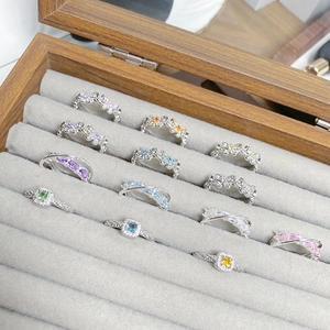 Close-up of assorted silver butterfly and gemstone rings on gray velvet tray