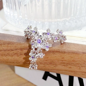 Detailed macro view of silver floral ring with purple zircon stones and tassels