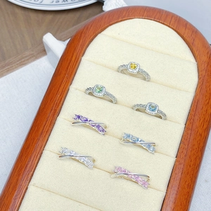 Detailed display of colorful zircon rings in halo and crisscross designs on a wooden stand