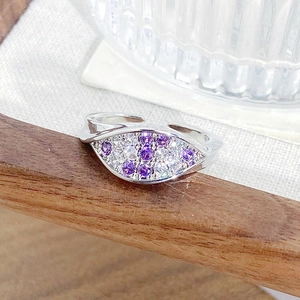 Macro detail of silver ring with marquise-cut purple and white zircon stones on linen