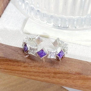 Macro shot of silver geometric ring featuring purple stones and sparkling zircon details