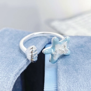 Détail de la bague étoile de mer et coquillage en émail bleu sur une boîte en velours