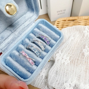 Detailed macro view of four colorful gemstone rings set in a blue velvet jewelry box