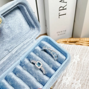 Close-up of light blue gemstone rings inside a luxury velvet jewelry storage box