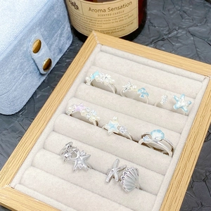 Détail de bagues en émail étoile de mer avec perles et zircon dans une boîte à bijoux en velours