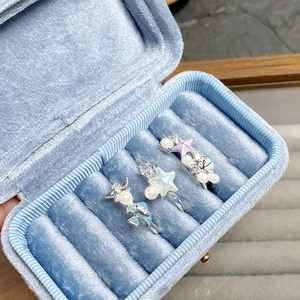 Détail de trois bagues océaniques avec perles et motifs d'étoiles dans un écrin bleu