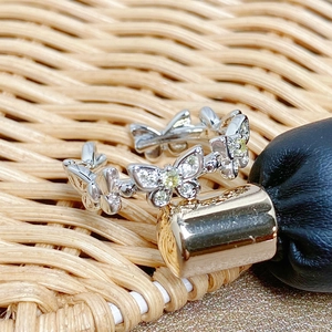 Macro detail of silver butterfly ring band featuring white zircons and yellow gemstones