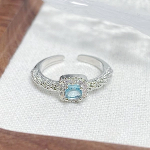 Detailed macro view of an adjustable silver ring with a blue square gemstone and zircon accents