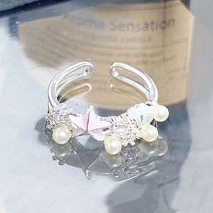 Vue macro d'une bague étoile de mer argentée avec émail rose, perles et zircons