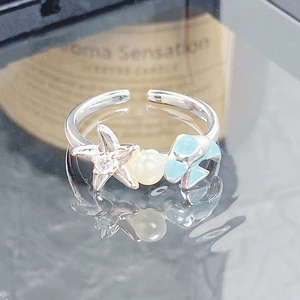Détail de la bague étoile de mer en émail avec perles et vernis bleu sur miroir