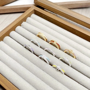 Makroaufnahme bunter Emaille-Ringe mit Zirkonia in einer Schmuckschatulle aus Holz