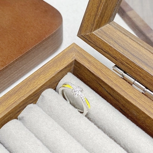 Makrodetail eines Silberknotenrings mit gelber Emaille und Pavé-Zirkon-Steinen