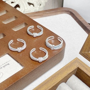 Detailansicht silberner Möbius-Knotenringe mit Zirkoniasteinen auf einem Holzständer