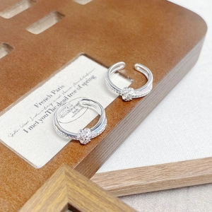 Detailansicht der silbernen Ringe mit Zirkonia und rosa Emaille auf einem Holzständer