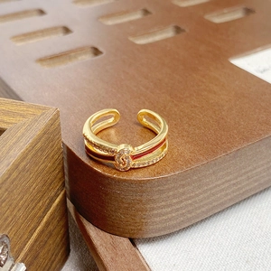 Detailaufnahme des goldenen Schleifenrings mit weißen Zirkonia und roter Emaille-Glasur