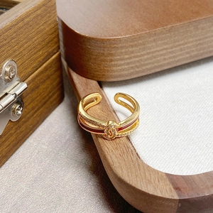 Detail eines vergoldeten offenen Rings mit roter Emaille und Zirkonia auf Holzbox
