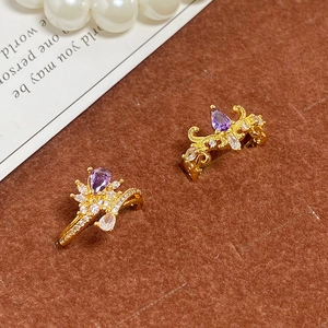 Détail de boucles d'oreilles couronne vintage dorées avec pierres violettes et zircons