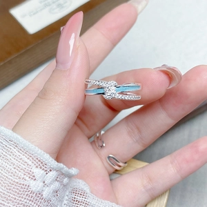 Detail eines silbernen Emaille-Schleifenrings mit Zirkonia-Pavé an der Hand auf Spitze