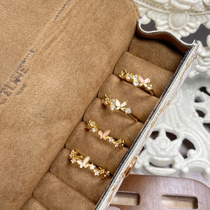 Set of four gold butterfly rings with cubic zirconia and enamel in a brown jewelry box