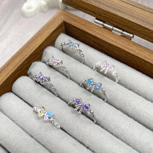 Detailed macro view of colorful zircon butterfly rings in a velvet wooden jewelry box