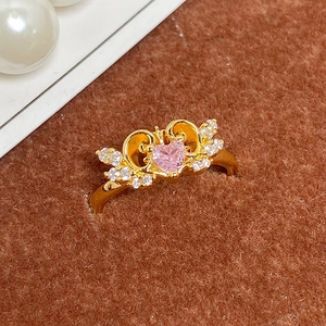 Vue macro d'une bague vintage dorée avec pierre rose en cœur et détails pavés fins