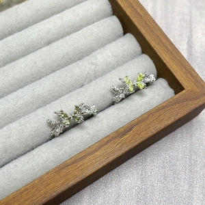 Detail of silver butterfly stud earrings with green zircon stones in a velvet jewelry box