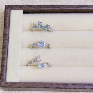 Detailed view of silver rings featuring butterfly, floral, and heart motifs with blue gems