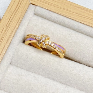 Detailansicht eines goldfarbenen Schleifenknotenrings mit lila Emaille und Zirkonia-Steinen
