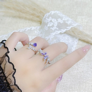 Close-up of adjustable silver rings with purple heart gemstone and floral cubic zirconia