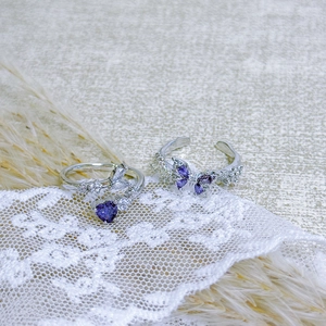 Close-up of butterfly and heart-shaped purple zircon rings on a wooden base