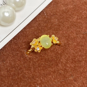 Gros plan sur bague vintage dorée torsadée avec pierre œil de chat et détails floraux