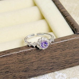 Close-up of adjustable silver flower ring with purple gemstone and crystal accents