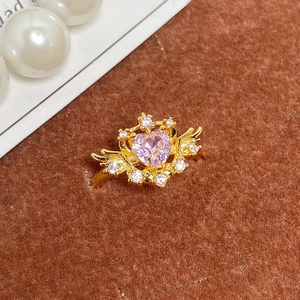 Vue macro d'une bague vintage dorée avec cœur en zircon rose et ailes d'ange
