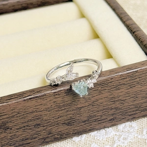 Macro view of adjustable silver ring with light blue heart gemstone and zircon details