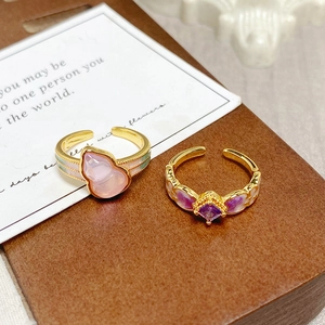 Detail of vintage enamel rings with pink gourd and purple square gemstones in gold finish