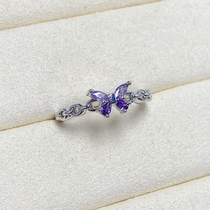 Macro shot of butterfly ring featuring purple marquise zircon and silver chain band