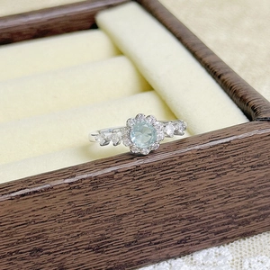 Detailed view of daisy ring with blue gemstone on beige velvet display holder