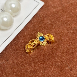 Détail de la bague vintage dorée avec pierre bleue et gravure baroque ajourée